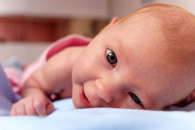 Close-up of cute baby boy lying on bed at home