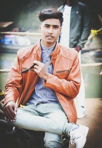 Portrait of young man wearing leather jacket while sitting outdoors