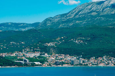 Aerial view of city by sea and mountain against sky