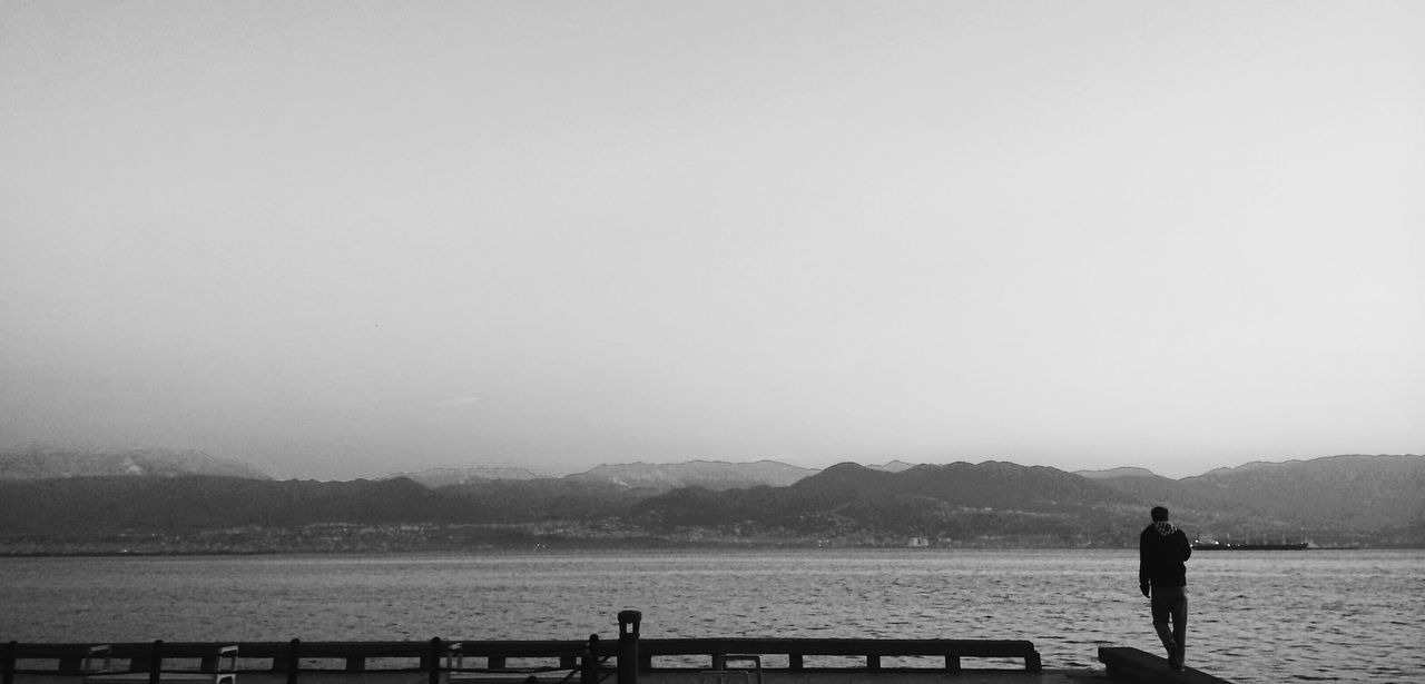 water, lifestyles, men, leisure activity, silhouette, standing, rear view, sea, tranquility, mountain, tranquil scene, scenics, copy space, lake, railing, person, beauty in nature