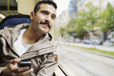 Young man looking through tram window