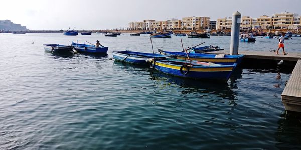 Boats moored in sea against buildings in city