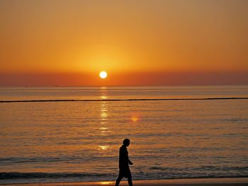 Silhouette man walking at beach during sunset