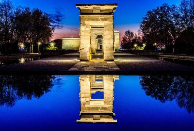 Reflection of built structure in water against blue sky