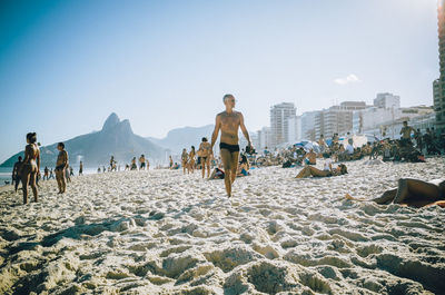 People walking on beach against clear sky