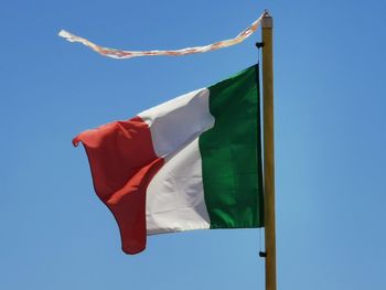 Low angle view of flag against blue sky