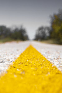 Surface level of yellow road against sky