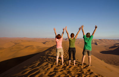 Rear view of people walking on desert against sky