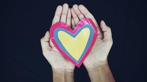 Close-up of hand holding heart shape paper against blurred background