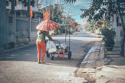 Rear view of woman pushing cart on street