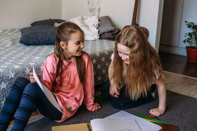 Rear view of mother and daughter reading book at home