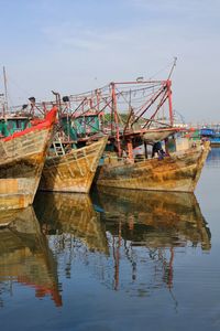 Fishing boat moored in lake against sky