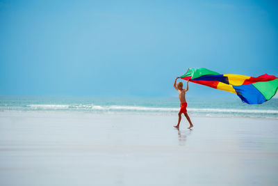 Rear view of woman holding umbrella against sky