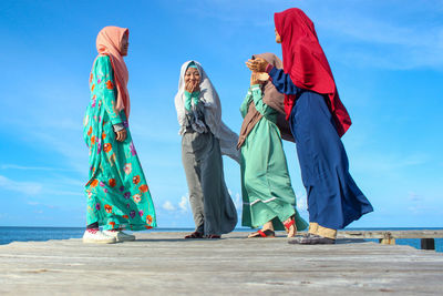 People standing by sea against blue sky