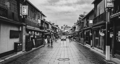 People walking on street in city against sky