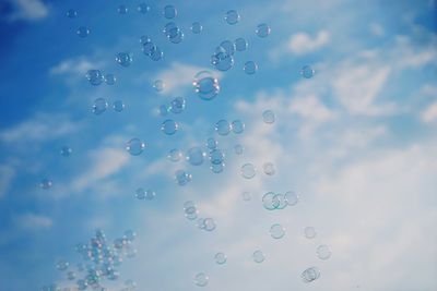 Low angle view of bubbles against rainbow in sky