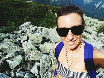 Portrait of young woman wearing sunglasses on rock