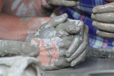 Cropped hands shaping pots at workshop