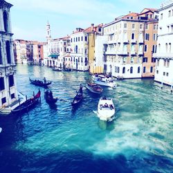 Boats in canal amidst buildings in city