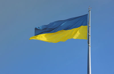 Low angle view of flag against clear blue sky