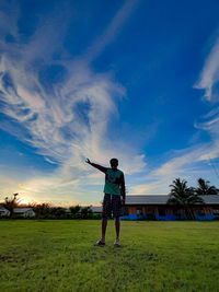 Man standing on field against sky at sunset