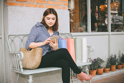 Full length of young woman sitting on chair outdoors