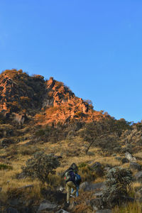 Man standing on rocks against clear blue sky