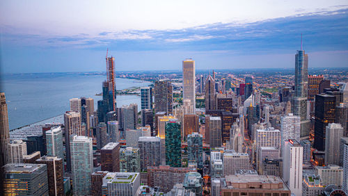 Aerial view of city buildings against cloudy sky