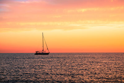 Sailboat in sea against sky during sunset