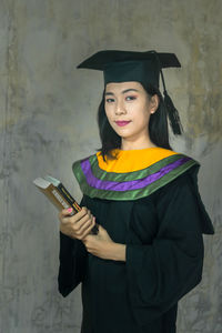 Portrait of a smiling young woman standing against wall