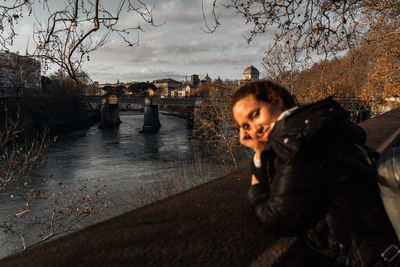 Portrait of young woman standing against river