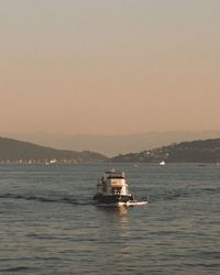 Boat sailing in sea against clear sky during sunset