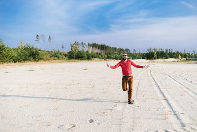 Full length of man with arms raised against sky