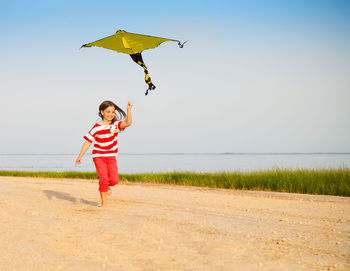 Full length of boy flying kite against sky