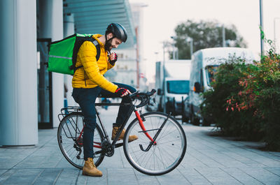 Man standing with bicycle on street in city