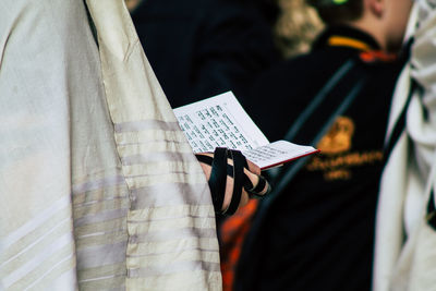 Midsection of man reading book on paper