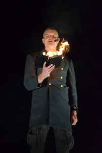 Mid adult man standing against black background