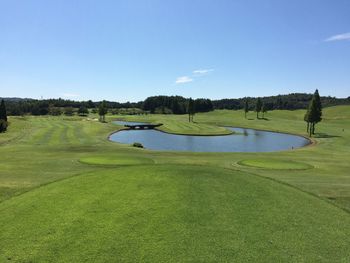 Scenic view of golf course against clear blue sky