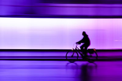 Side view of silhouette man against illuminated city at night