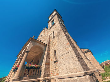 Stone ancient church on background of blue sky. stone stairs, arched windows, high tower.