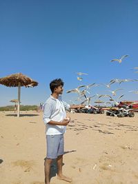 Man standing on beach against clear blue sky