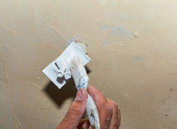 Midsection of person holding paper against wall