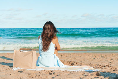 Rear view of woman standing at beach