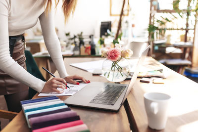 Midsection of woman using mobile phone while sitting on table