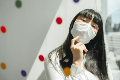 Portrait of young woman holding white wall