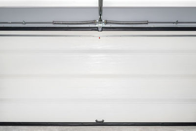 A closed garage door with an electric drive, four sections, a view straight from the garage.