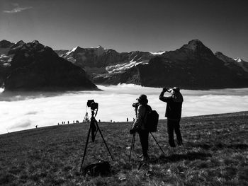 People photographing on field against mountains