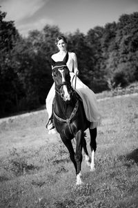 Bride riding horse on field