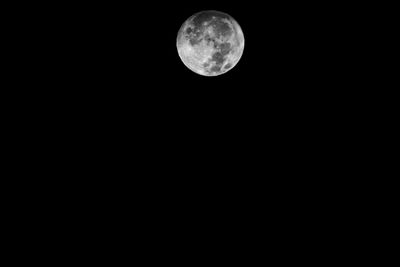 Low angle view of full moon against black sky