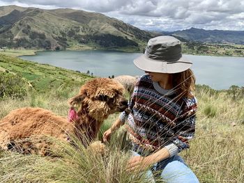 Portrait of woman sitting on field with alpaca 